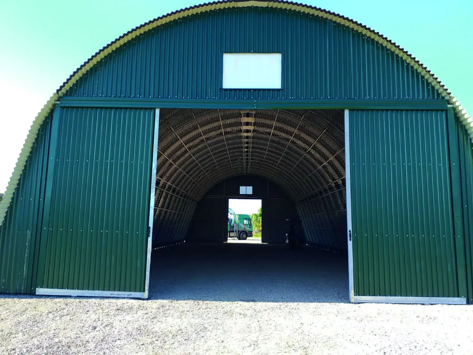 Tunnel de stockage à arches avec grandes portes coulissantes ouvertes pour le passage des véhicules
